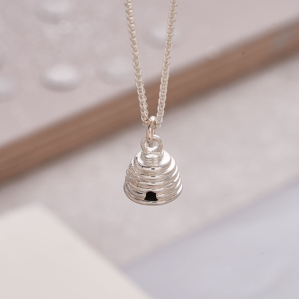 Silver beehive charm with detailed texture, displayed on a white background by Scarlett Jewellery.