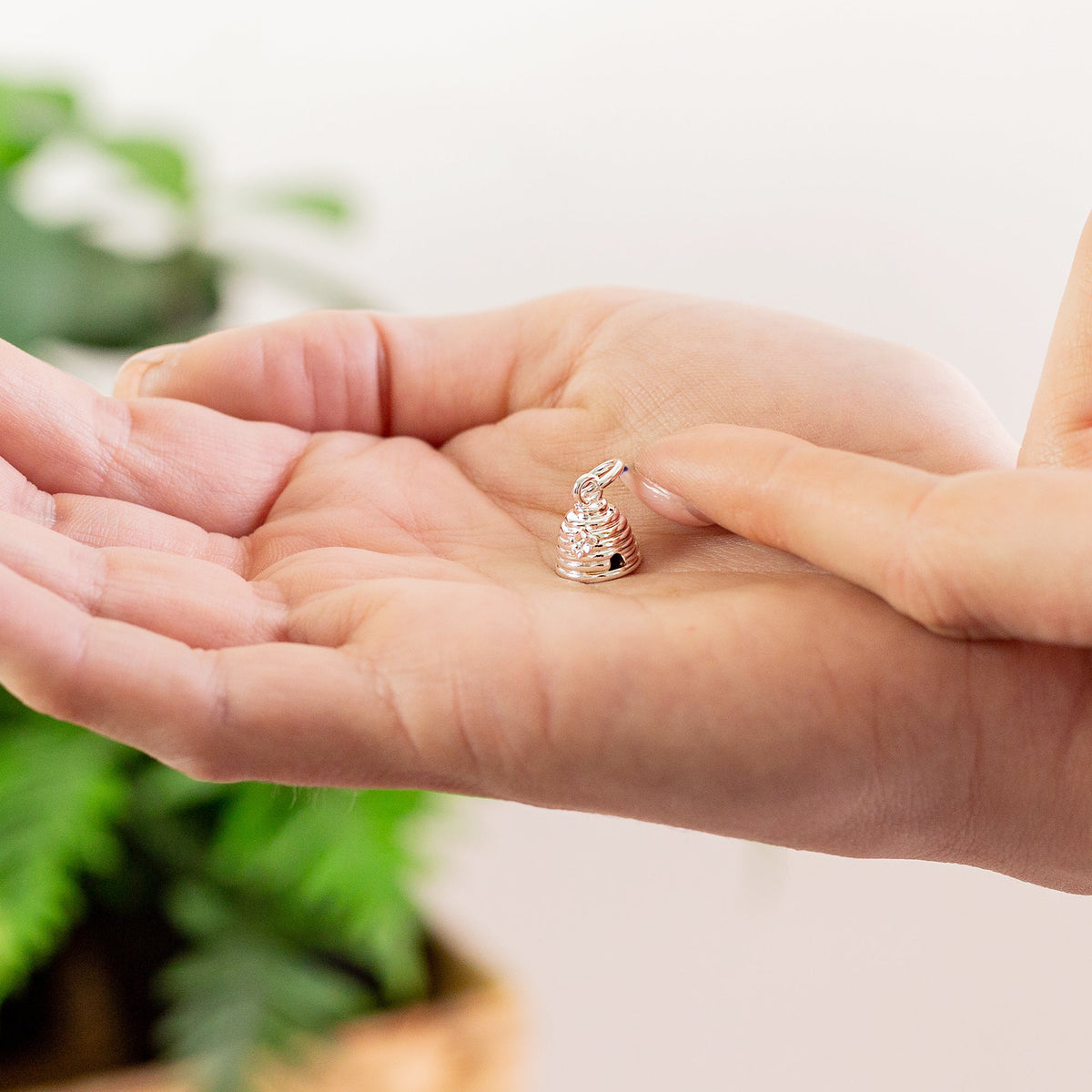 A silver beehive charm with intricate detailing, displayed on a soft white background, by Scarlett Jewellery.
