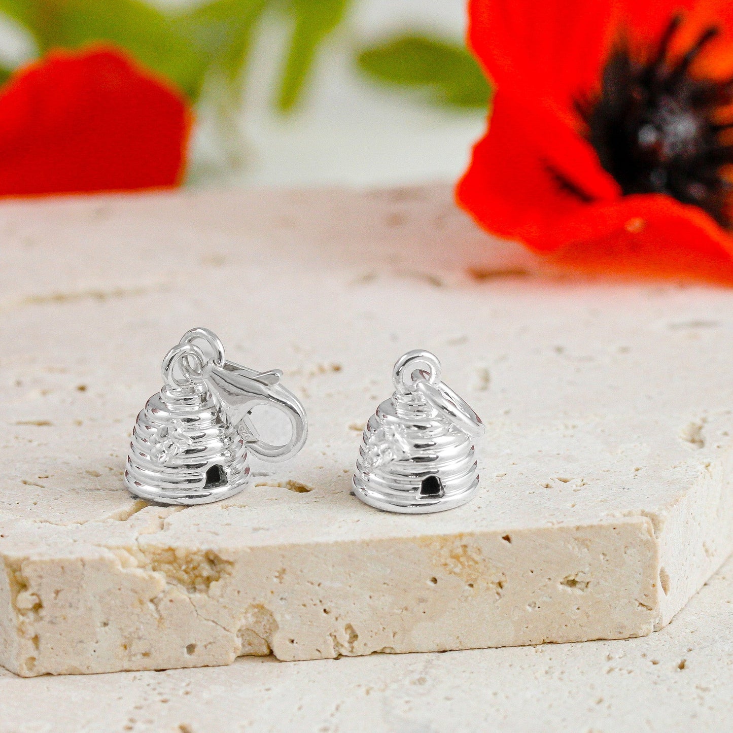 A silver beehive charm with intricate detailing, displayed on a soft white background, by Scarlett Jewellery.