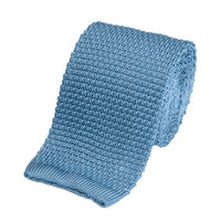 A knitted silk tie in sky blue with a subtle texture, shown folded neatly on a white background.