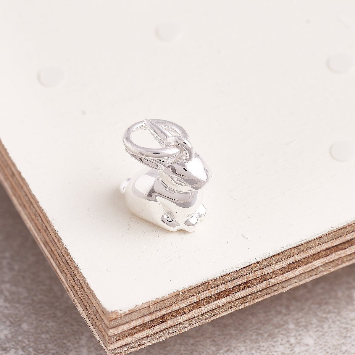 A silver bunny rabbit charm shaped like a small statue, detailed and shiny, by Scarlett Jewellery.