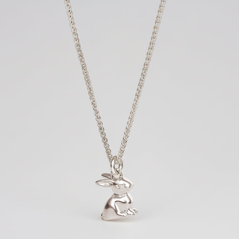 A silver bunny rabbit charm with detailed texture, shown against a soft background, by Scarlett Jewellery.