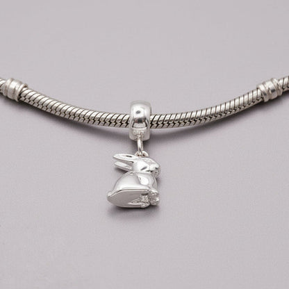 A silver bunny rabbit charm with detailed texture, shown against a soft background, by Scarlett Jewellery.