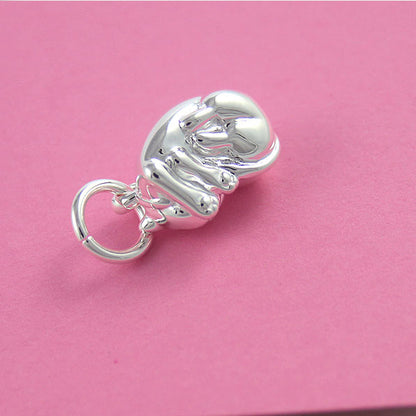 A silver cat charm with intricate detailing, displayed on a soft fabric background, by Scarlett Jewellery.