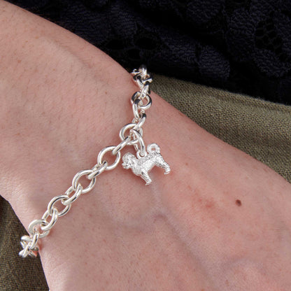 A silver cavapoo dog charm hangs on a chain, detailed and elegant, by Scarlett Jewellery.