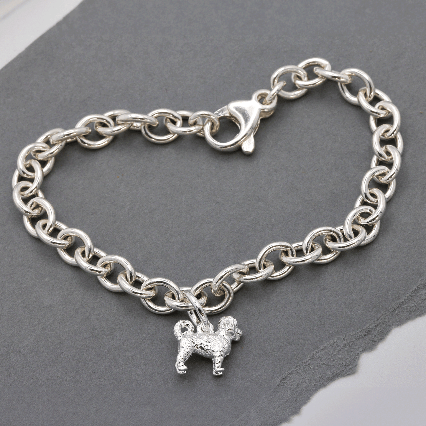 A silver cavapoo dog charm shaped like a small dog, detailed with a smooth finish and delicate features, by Scarlett Jeweller