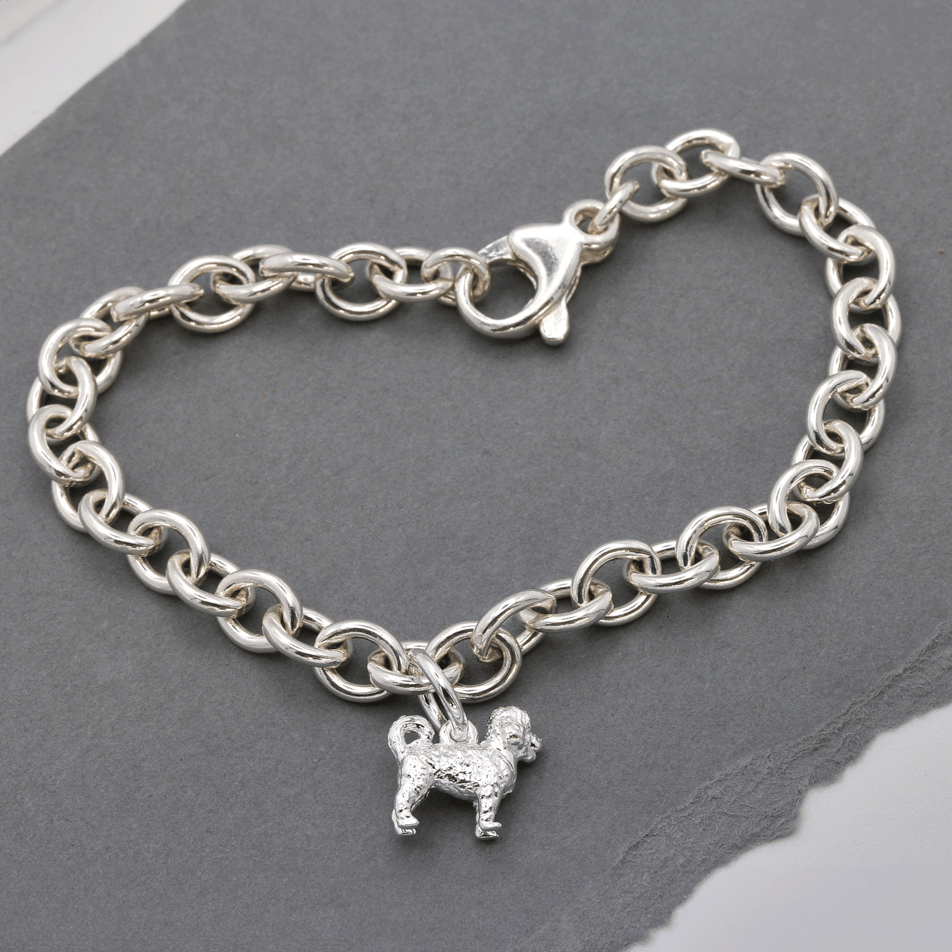 A silver cavapoo dog charm shaped like a small dog, detailed with a smooth finish and delicate features, by Scarlett Jeweller