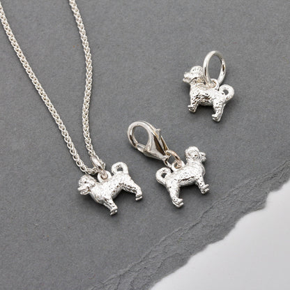A silver cavapoo dog charm shaped like a small dog, detailed with a soft texture, by Scarlett Jewellery.