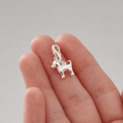 A silver chihuahua dog charm with detailed facial features, displayed on a soft pink background by Scarlett Jewellery.