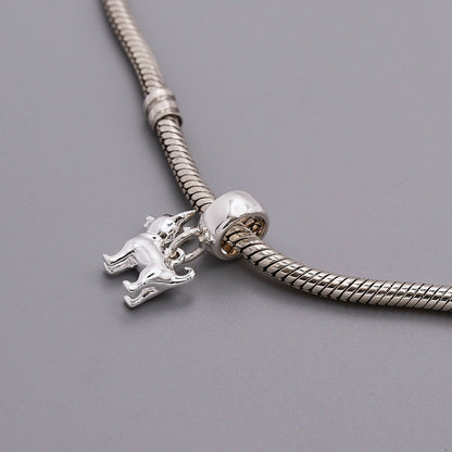 A silver chihuahua dog charm with detailed facial features, displayed on a soft pink background by Scarlett Jewellery.