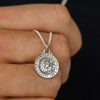 Silver St Christopher pendant on a chain with personalized engraving, styled on a wooden table.