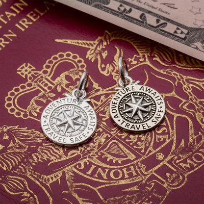 Silver compass charm with personalized engraving, styled on a travel-themed background by Scarlett Jewellery.