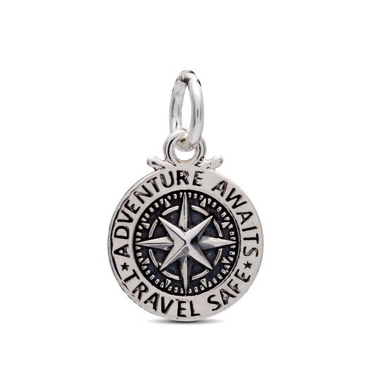 A silver travel safe compass charm with personalized engraving, displayed on a soft background by Scarlett Jewellery.