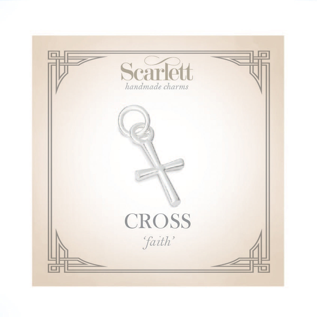 A silver cross charm glinting on a velvet background, detailed engravings visible, by Scarlett Jewellery.