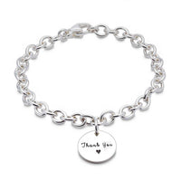 A silver round tag charm bracelet with personalized engraving, featuring a delicate chain and circular design by Scarlett Jew