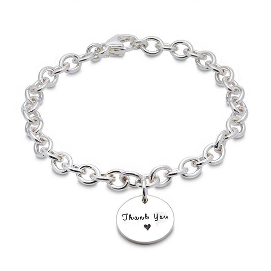 A silver round tag charm bracelet with personalized engraving, featuring a delicate chain and circular design by Scarlett Jew