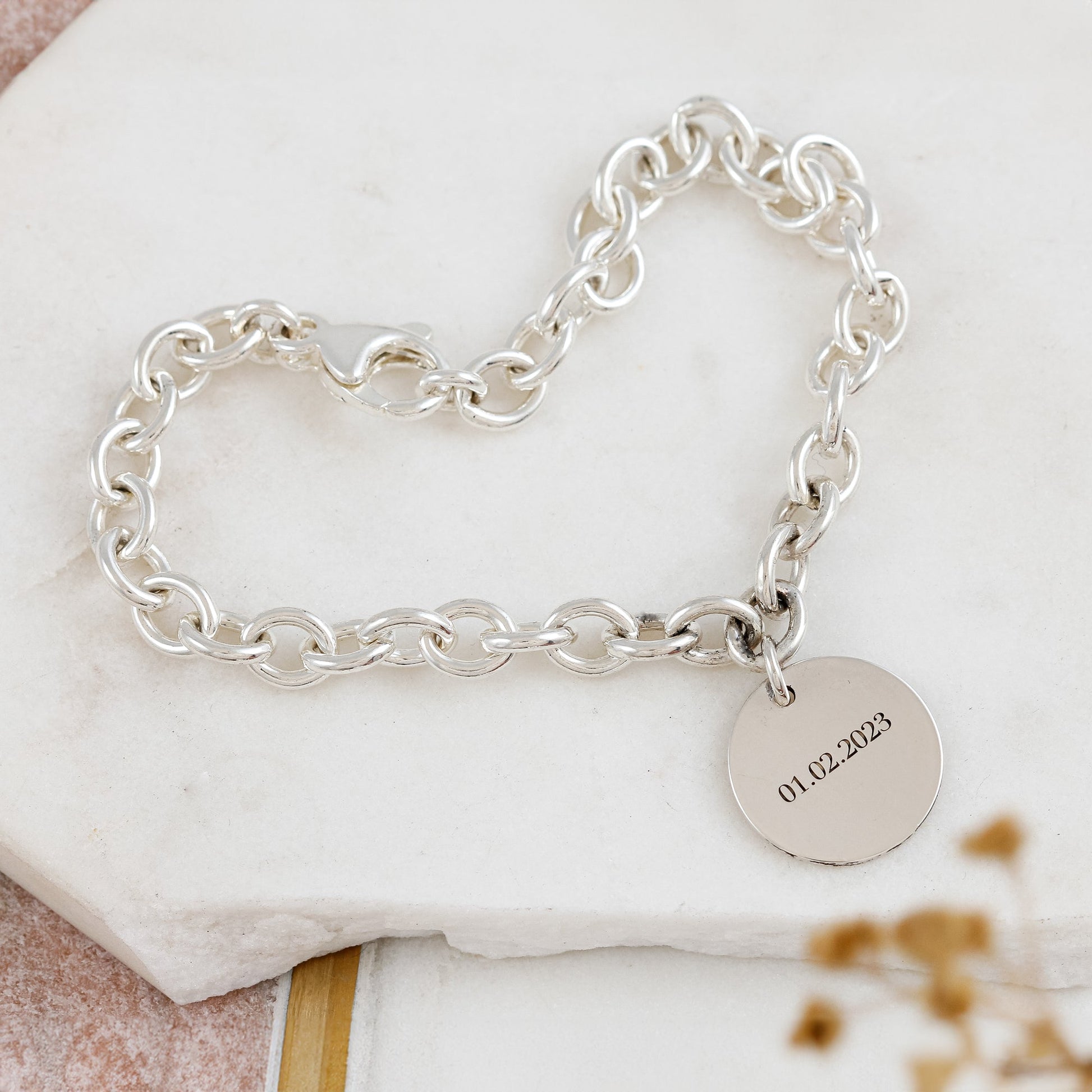 A silver round tag charm bracelet with personalized engraving, featuring a delicate chain and circular design by Scarlett Jew