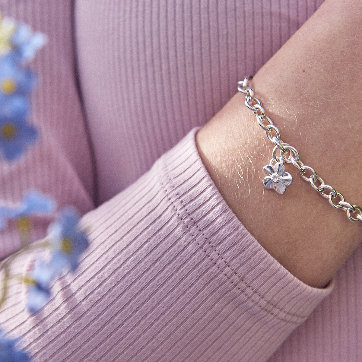 Silver forget-me-not flower charm with personalized engraving, styled on a necklace chain by Scarlett Jewellery.