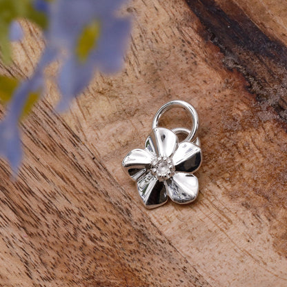 A silver forget-me-not flower charm with delicate petals, personalized engraving, and a polished finish by Scarlett Jewellery