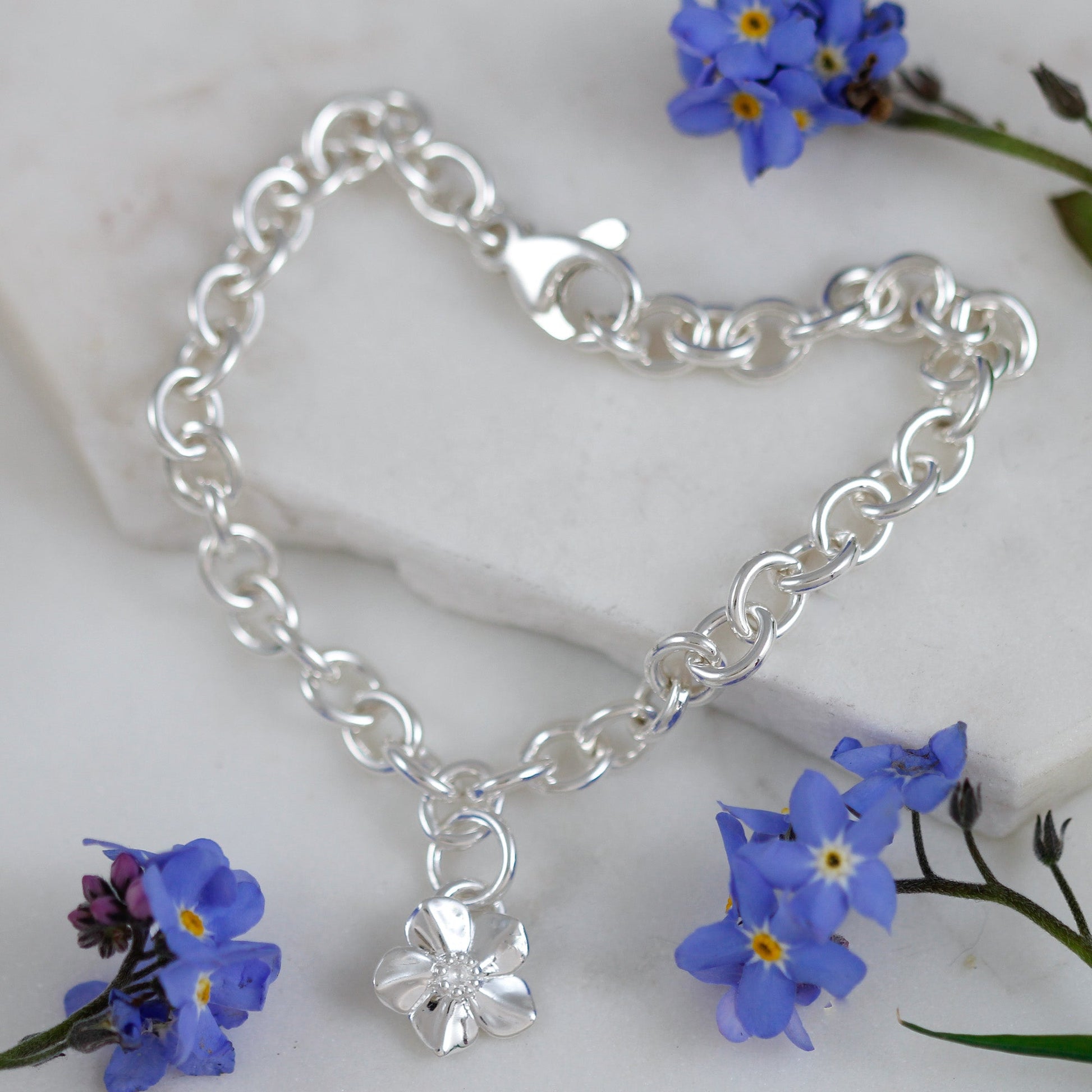 A silver personalised charm bracelet with a forget-me-not design by Scarlett Jewellery