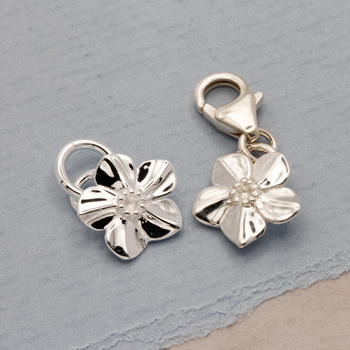 Silver forget-me-not flower charm with personalized engraving, styled on a necklace chain by Scarlett Jewellery.