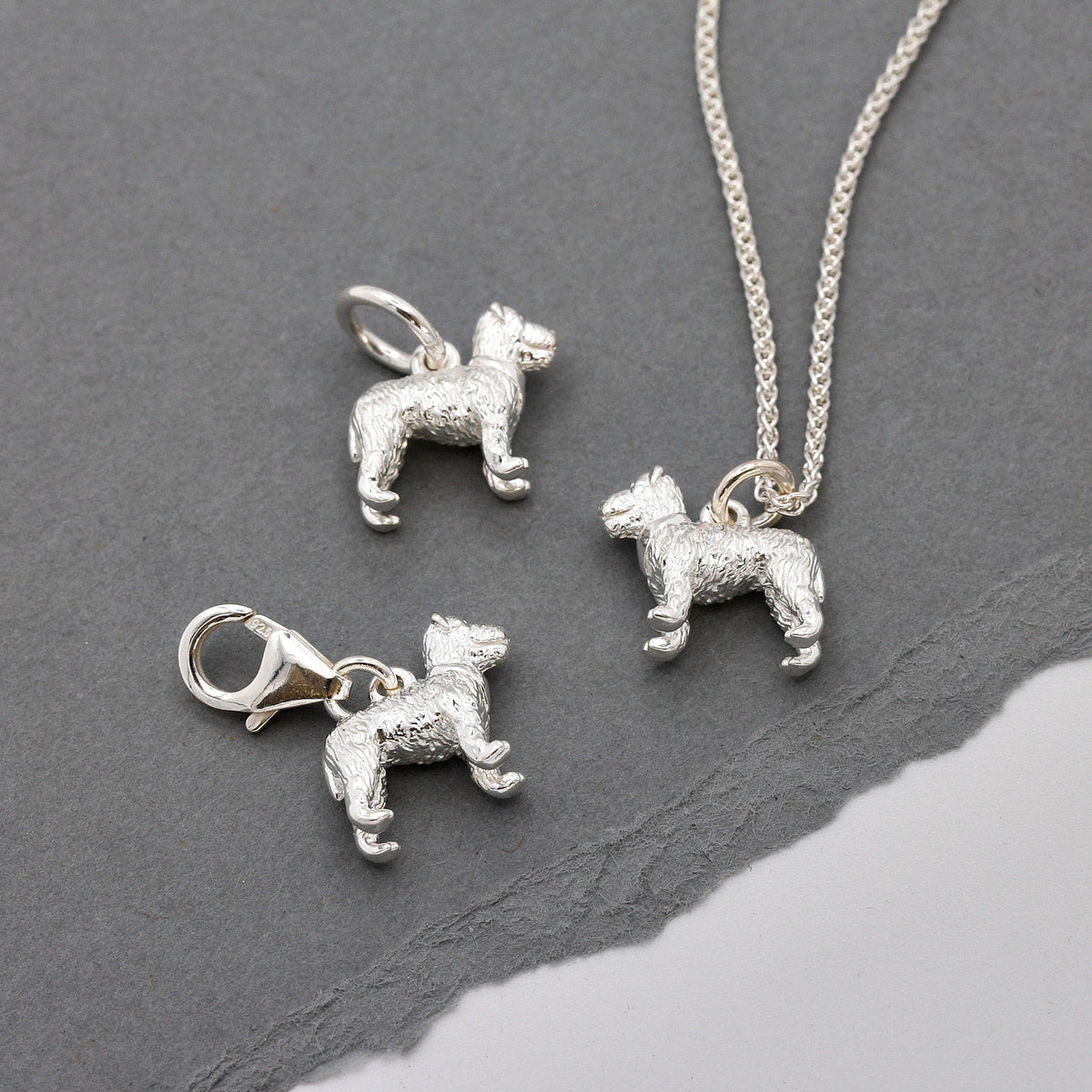 A silver fox terrier dog charm shaped like a paw print, displayed on a soft white background by Scarlett Jewellery.
