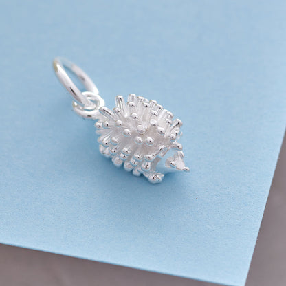 A silver hedgehog charm shaped like a small ball, detailed with texture and spikes, by Scarlett Jewellery.