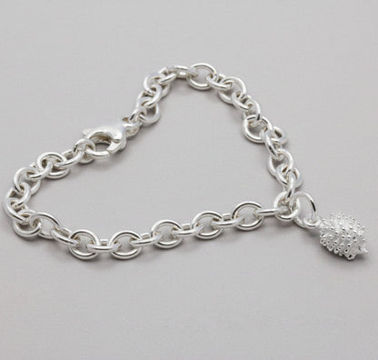 Silver hedgehog charm with intricate detailing, displayed on a soft velvet background, part of the Scarlett Jewellery collect