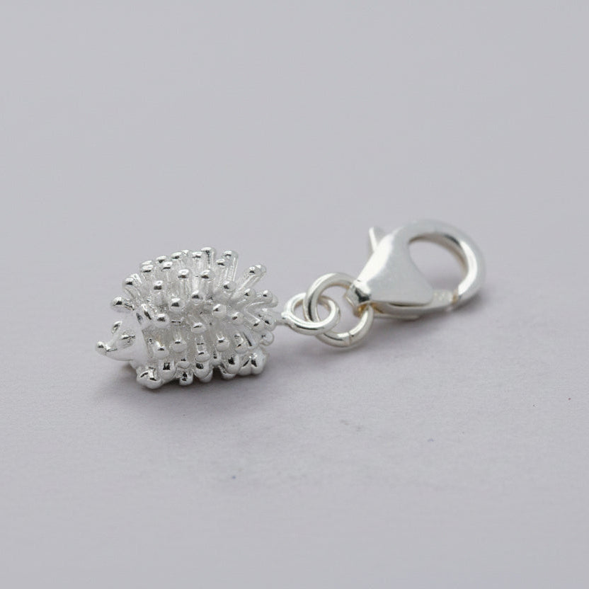 Silver hedgehog charm with intricate detailing, displayed on a soft velvet background, part of the Scarlett Jewellery collect