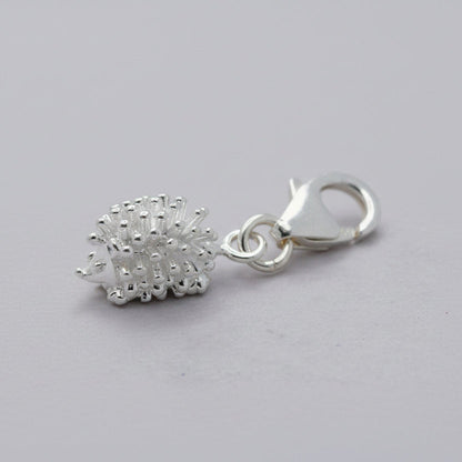 Silver hedgehog charm with intricate detailing, displayed on a soft velvet background, part of the Scarlett Jewellery collect