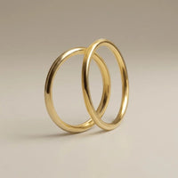 A slim 2mm gold wedding band set in 9ct gold, displayed on a soft white background by Majestic Jewellery.