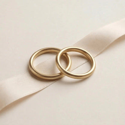 A slim 2mm gold wedding band set in 9ct gold, displayed on a soft white background by Majestic Jewellery.