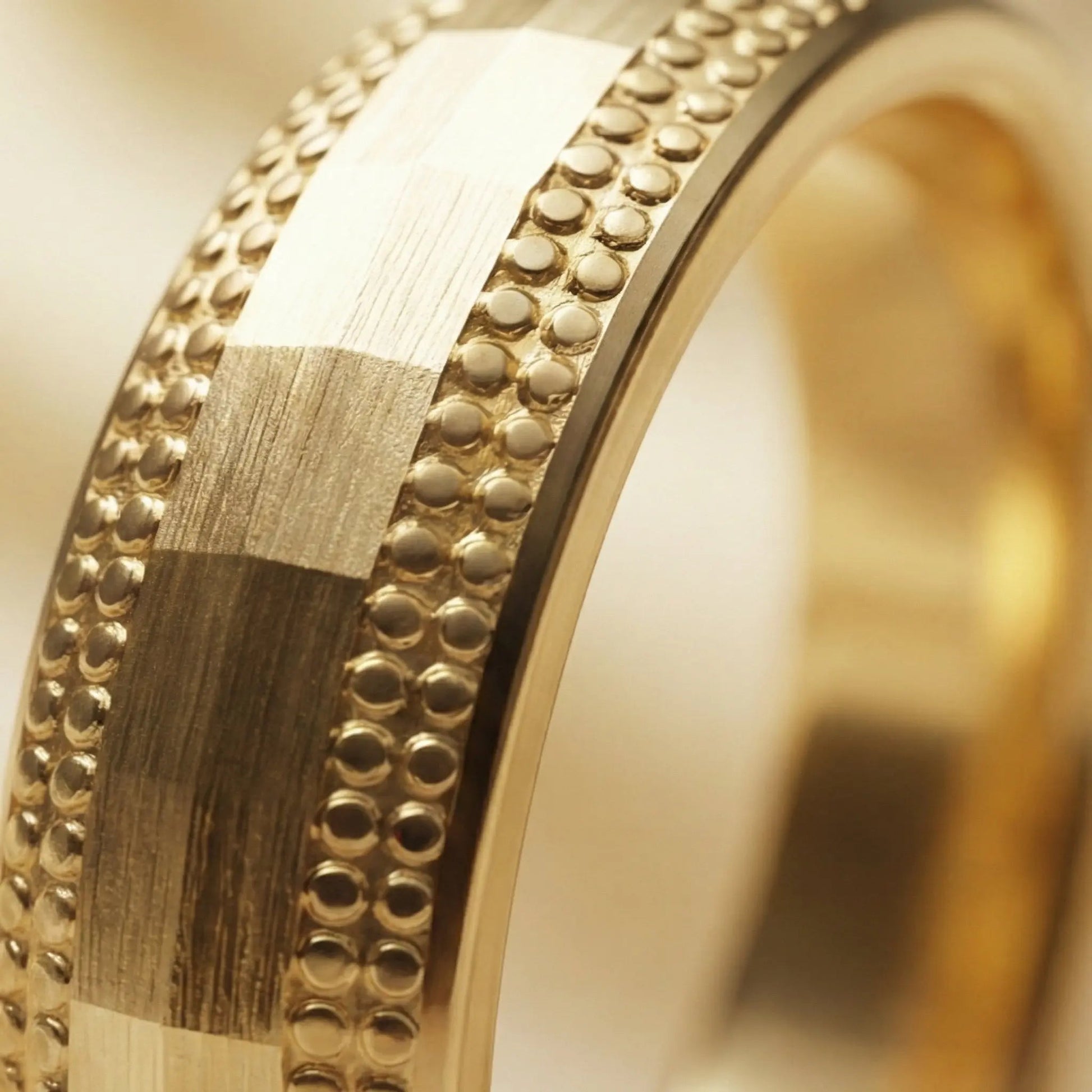 A 5mm gold wedding band with faceted milgrain detailing in 9ct gold, shown against a black background by Majestic Jewellery.
