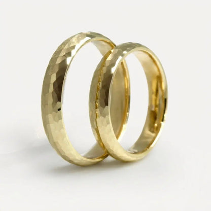 A 4mm faceted gold wedding band in 9ct gold, displayed on a white background with a subtle texture and reflective shine by Ma