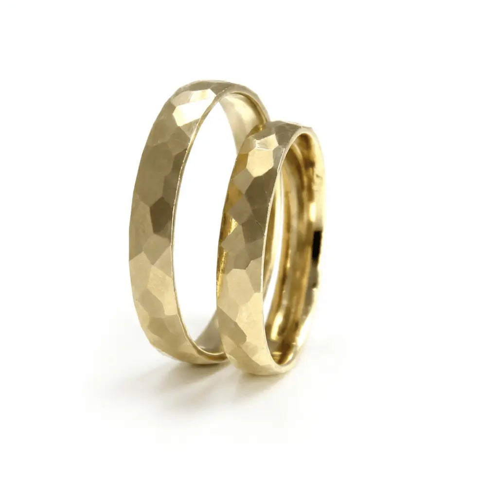 A hammered faceted 3.5mm gold wedding band in 9ct gold worn on a finger by Majestic Jewellery.