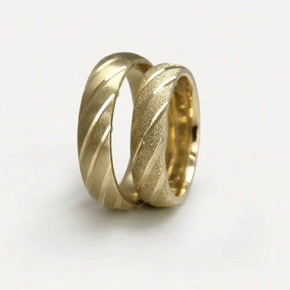 A 5mm gold wedding band with diagonal contrast design in 9ct gold, shown against a black background by Majestic Jewellery.