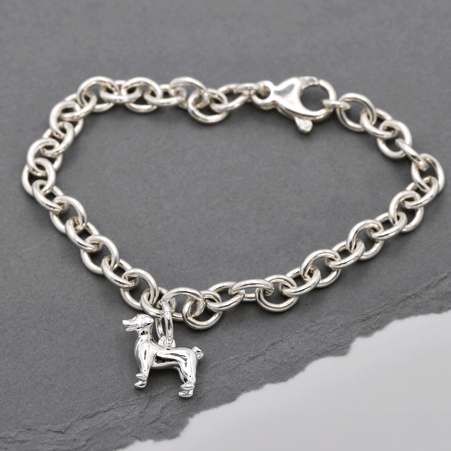Silver Jack Russell Terrier dog charm by Scarlett Jewellery displayed on a soft fabric background.