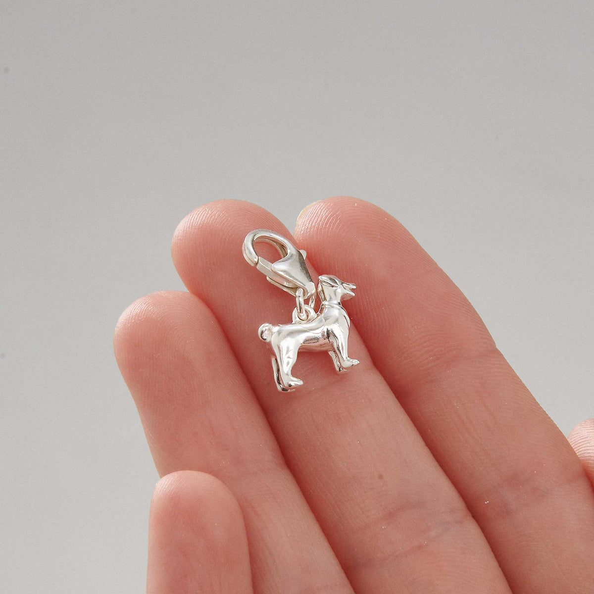 Silver Jack Russell Terrier dog charm by Scarlett Jewellery displayed on a soft fabric background