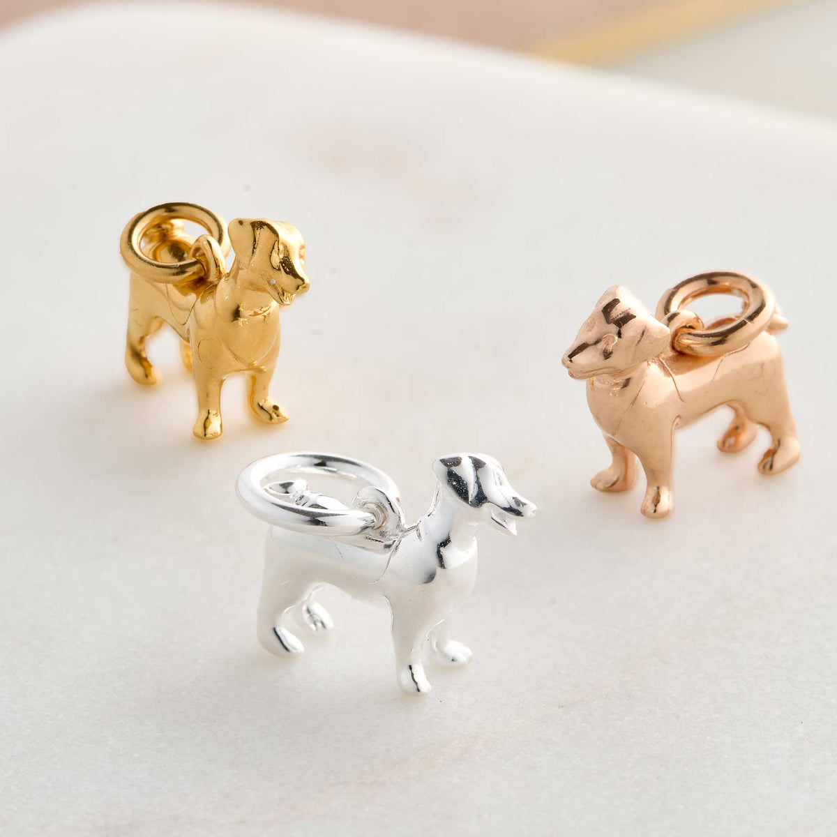 Silver Jack Russell Terrier dog charm by Scarlett Jewellery displayed on a soft fabric background.