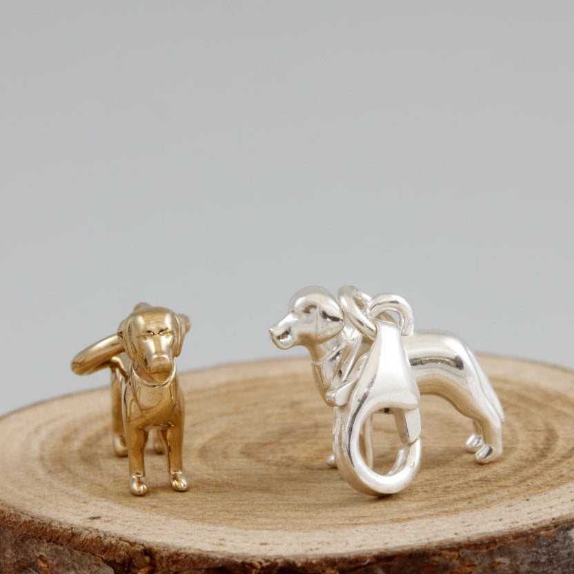 A silver Labrador dog charm with detailed texture, displayed on a soft blue background by Scarlett Jewellery.
