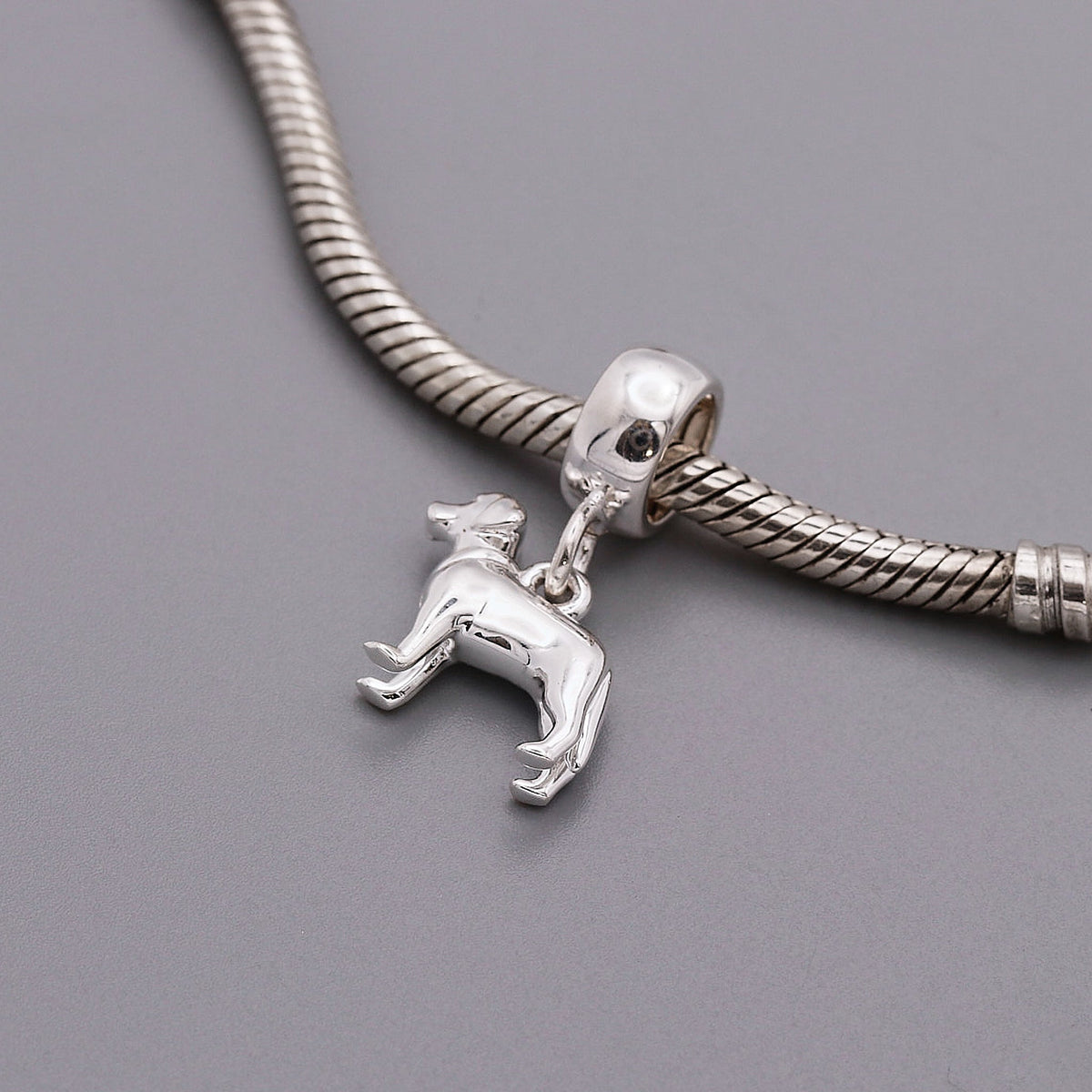 A silver Labrador dog charm shaped like a loyal companion, displayed on a soft background, by Scarlett Jewellery.