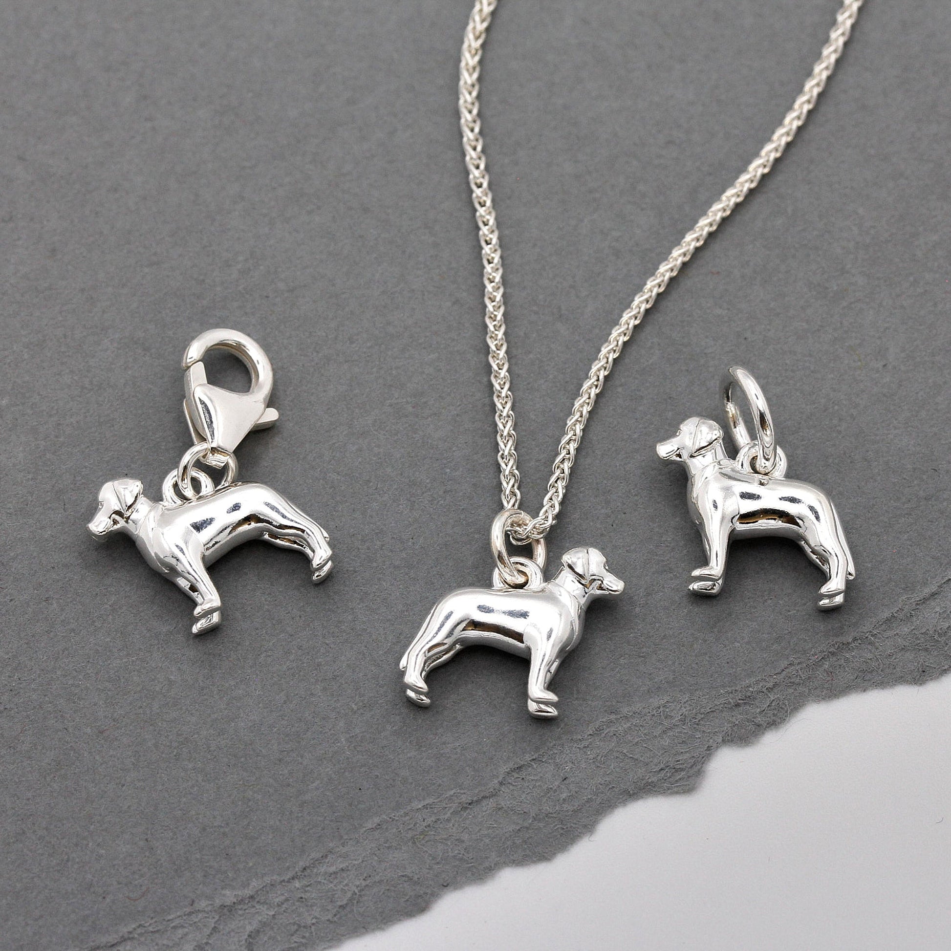 A silver Labrador dog charm shaped like a paw print, displayed on a white background with a soft texture, by Scarlett Jewelle