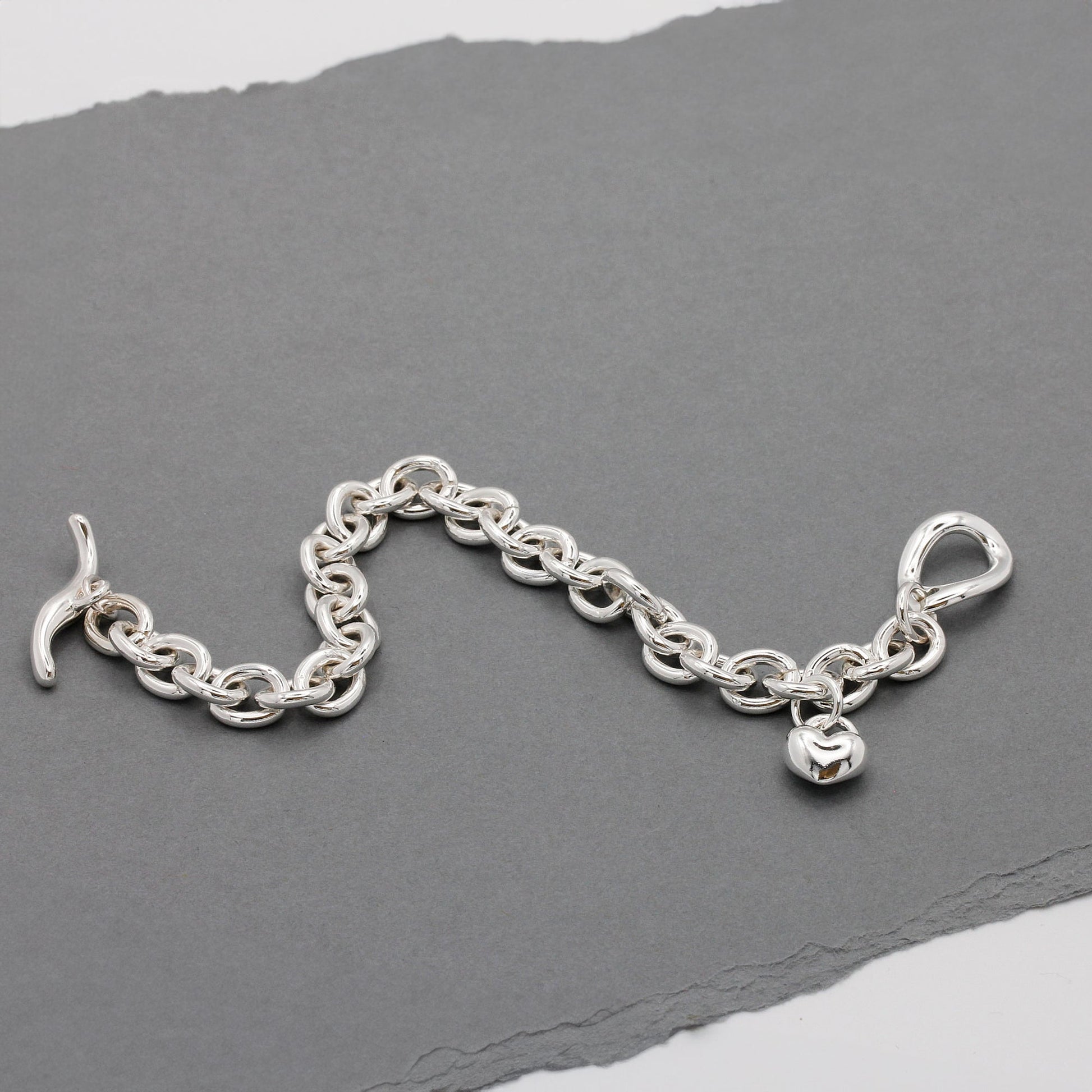 Silver heart charm bracelet with delicate chain and engraved details by Scarlett Jewellery.