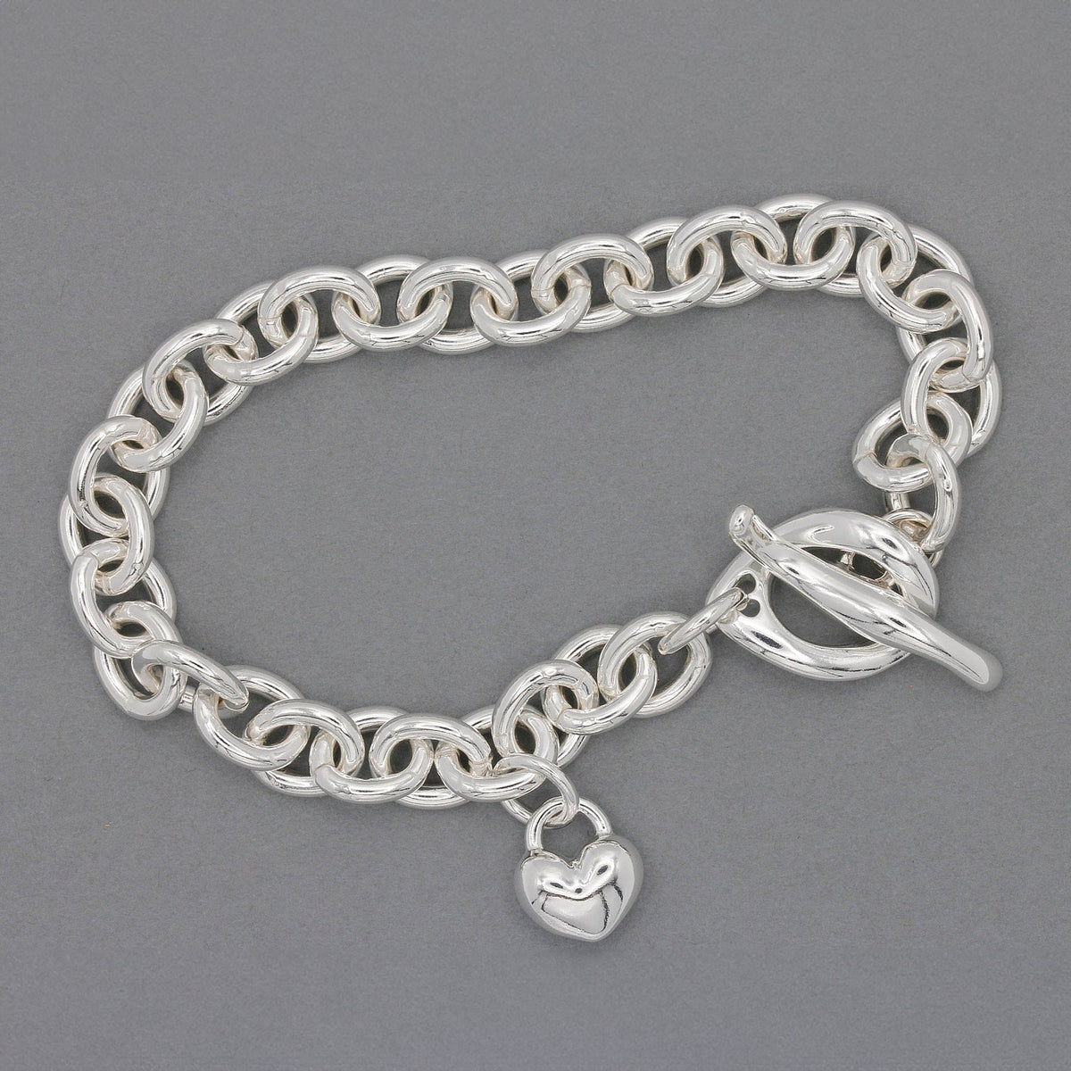 Silver heart charm bracelet with delicate chain and engraved details by Scarlett Jewellery.