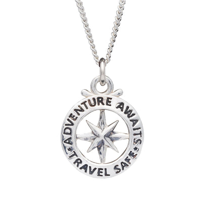 A large silver necklace featuring an outline compass and the name St Christopher, displayed against a dark background by Scar