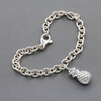 Silver pineapple charm with detailed texture, shown against a clean background, by Scarlett Jewellery.