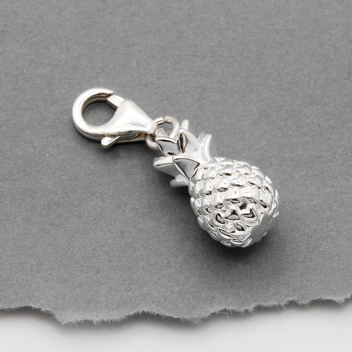 Silver pineapple charm with detailed texture, shown against a white background, by Scarlett Jewellery.