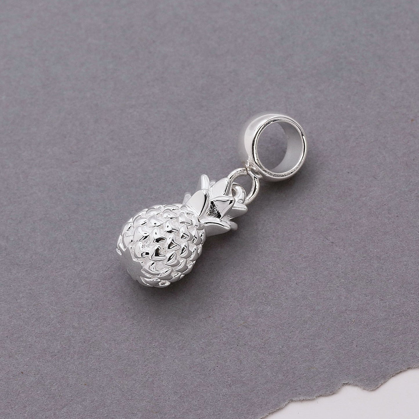 Silver pineapple charm with detailed texture, shown against a white background, by Scarlett Jewellery.