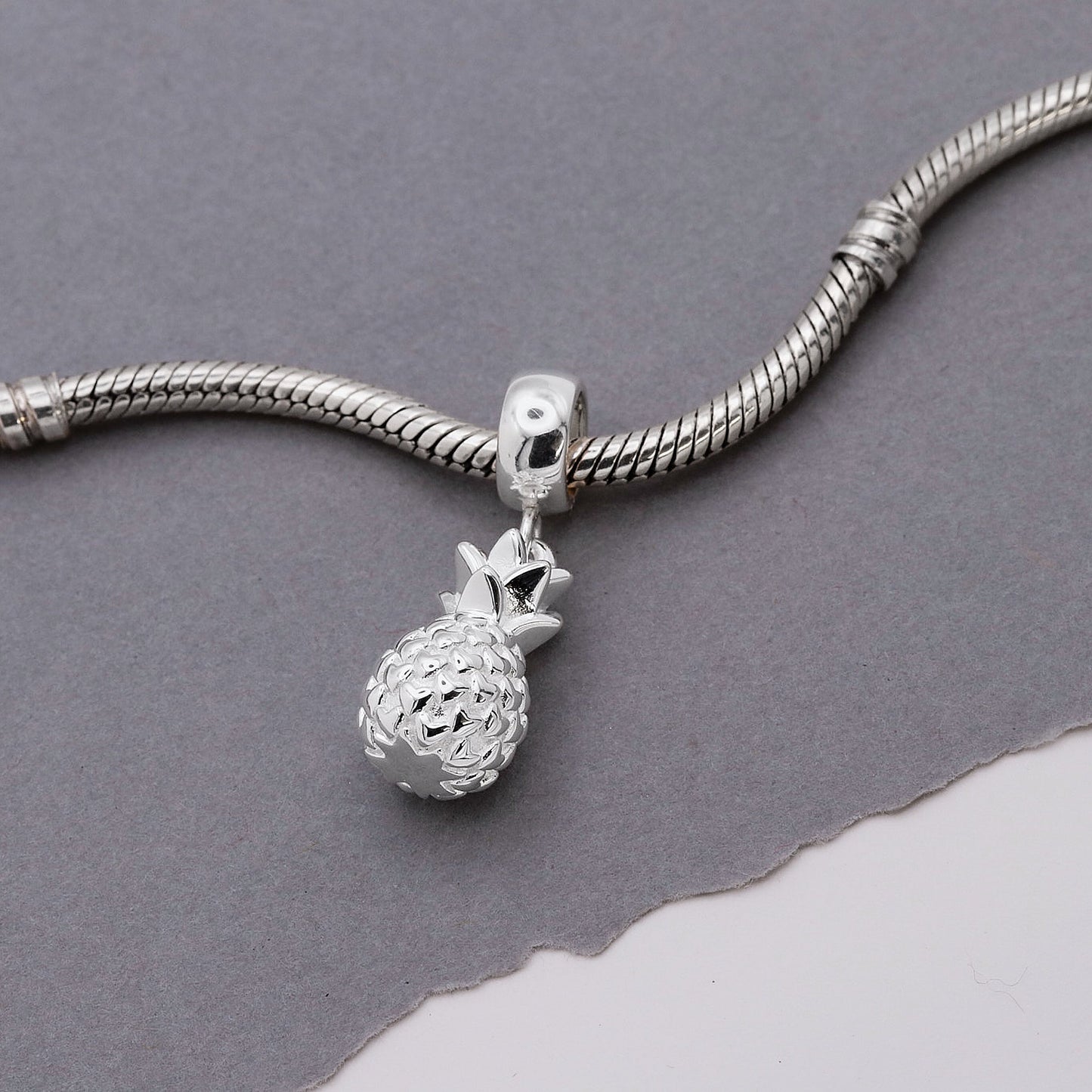 Silver pineapple charm with detailed texture, shown against a white background, by Scarlett Jewellery.