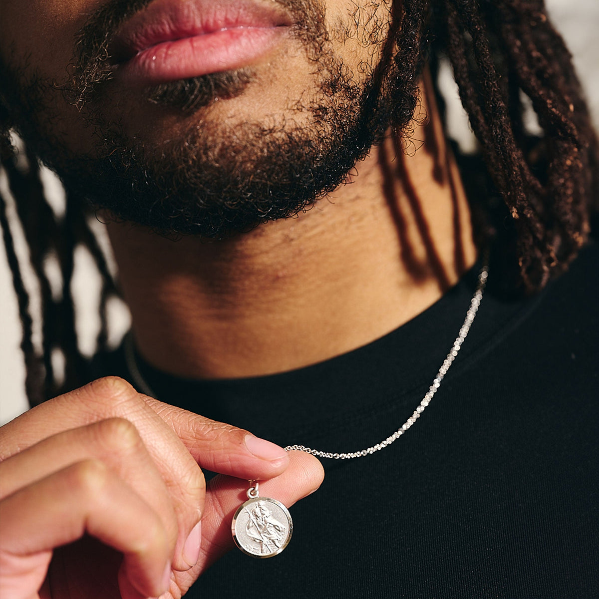 A sterling silver St Christopher pendant hangs on a delicate chain, showcasing its intricate design and elegant finish by Sca